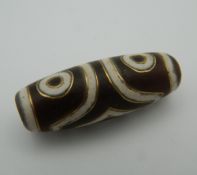 A gold inlaid dzi bead. 3.5 cm long.