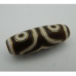 A gold inlaid dzi bead. 3.5 cm long.