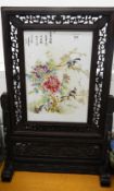 A Chinese porcelain screen in carved wooden stand. 67 cm high.