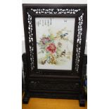 A Chinese porcelain screen in carved wooden stand. 67 cm high.