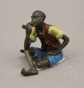 A cold painted bronze model of a boy smoking a pipe. 6 cm high.