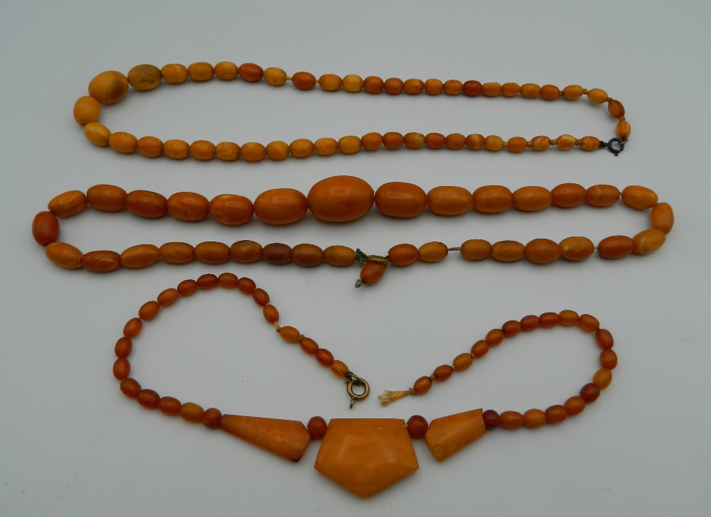 An amber bead necklace and two others. The largest 48 cm long.
