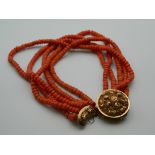 A string of coral beads with an unmarked 18 ct gold clasp. 43 cm long.