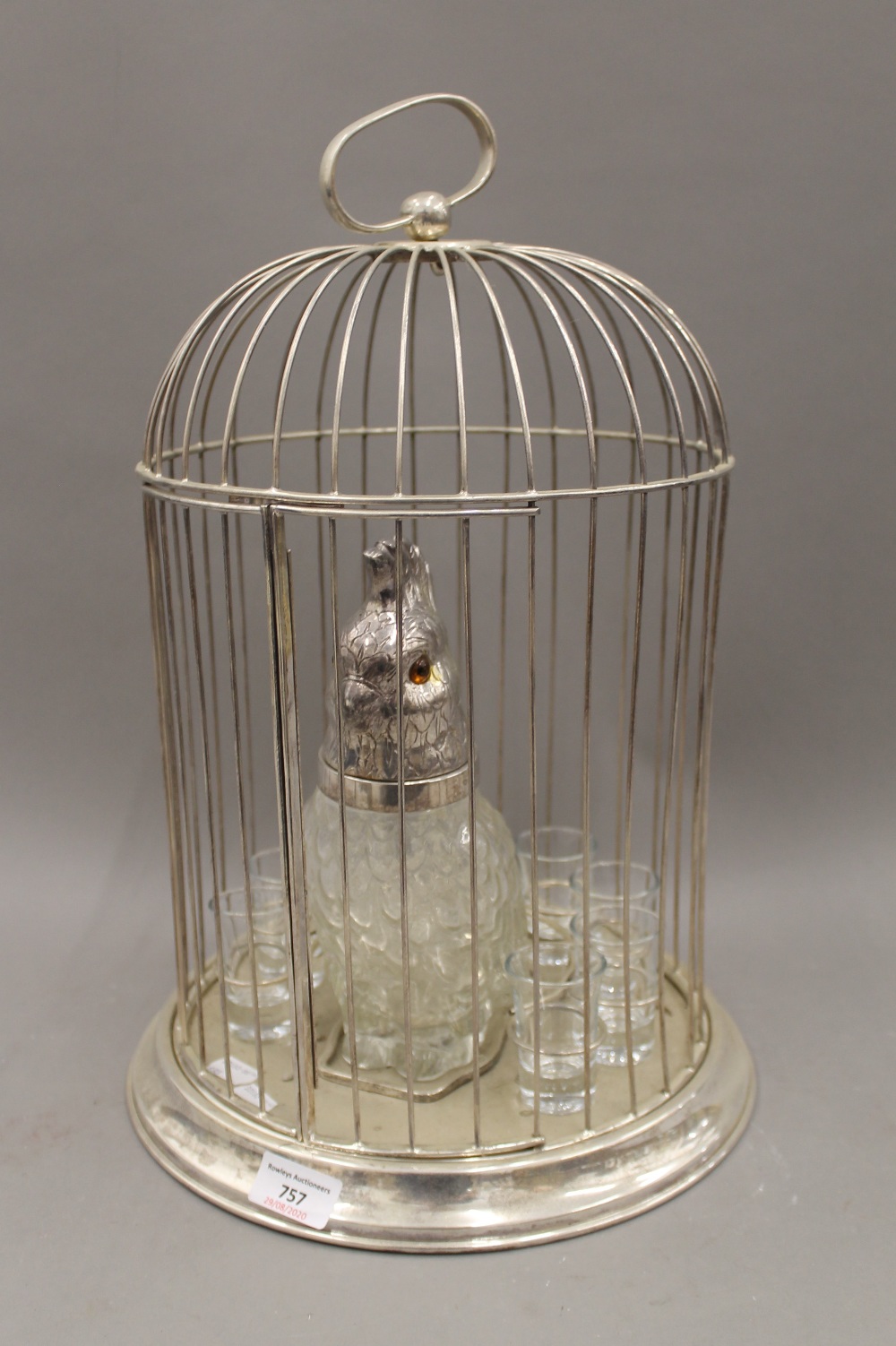 A silver plated bird cage drink set, incorporating a parrot form decanter and shot glasses.