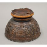 A 19th century Chinese carved coconut cup, mounted on a wooden stand. 7 cm high.