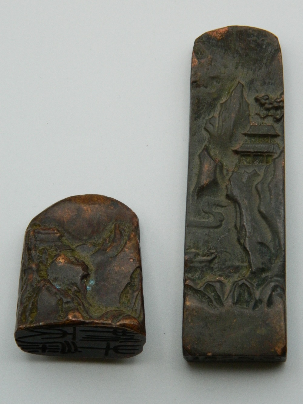 Two Chinese bronze seals decorated with mountainous landscapes. The largest 9 cm high.