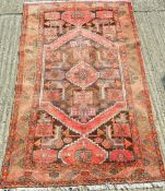 A Persian red ground wool rug. 200 x 128 cm.