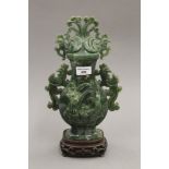 A spinach jade vase and cover, with phoenix decoration on a hardwood stand. 37.5 cm high.