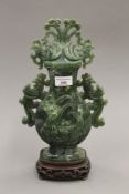 A spinach jade vase and cover, with phoenix decoration on a hardwood stand. 37.5 cm high.