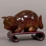A Chinese agate animalier carving Formed as a cat, mounted on a wooden stand. 9 cm long.