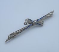 An Edwardian platinum diamond and sapphire bow brooch with an 18 ct gold pin.