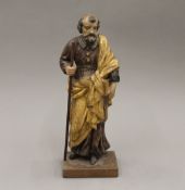 An 18h century carved figure holding a staff and a book, mounted on a plinth base. 36 cm high.