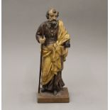 An 18h century carved figure holding a staff and a book, mounted on a plinth base. 36 cm high.