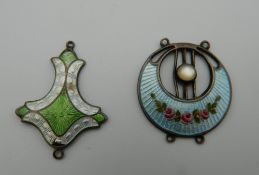 Two Art Nouveau enamel decorated silver pendants. The largest 3 cm high.