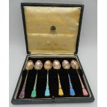 A cased set of silver and enamel spoons.