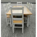 A modern white painted oak dining table and a set of eight ladder back dining chairs.