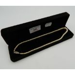 A string of pearls, housed in a black velvet box. 39 cm long.