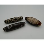 Three agate dzi beads. The largest 5.5 cm long.