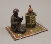 A cold painted bronze inkwell formed as an Arab and a coffee table on a rug. 14 cm wide.