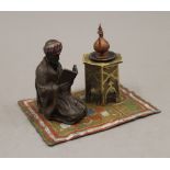 A cold painted bronze inkwell formed as an Arab and a coffee table on a rug. 14 cm wide.