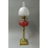 A Victorian oil lamp with cranberry glass reservoir. 76 cm high.