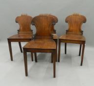 A set of four early 19th century mahogany hall chairs. 42.5 cm wide.