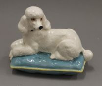 A Beswick model of a poodle on a cushion. 18 cm wide.