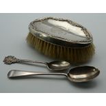 A silver brush and two silver teaspoons.