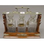 A silver plate mounted oak three bottle tantalus. 38.5 cm wide.