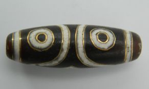 A gold inlaid dzi bead. 3.5 cm long.