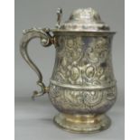 A silver plated lidded tankard, with embossed decoration. 20 cm high.
