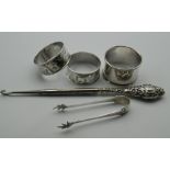 Three silver napkin rings, a pair of silver tongs and a button hook. 67.