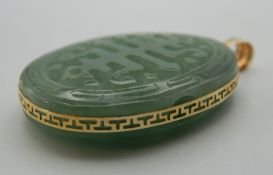 A 14 K gold and carved jade oval pendant. 5 cm high.
