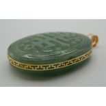 A 14 K gold and carved jade oval pendant. 5 cm high.