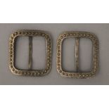 A pair of unmarked white metal buckles. Each 5 cm wide.