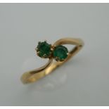 A 9 ct gold and emerald wishbone ring. Ring Size P. 1.4 grammes total weight.