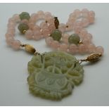 A carved jade pendant on a carved jade and rose quartz necklace. The pendant 6 cm wide.