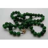 A string of jade carved beads set with an 18 K gold clasp. 102 cm long.