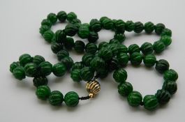 A string of jade carved beads set with an 18 K gold clasp. 102 cm long.