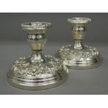 A pair of sterling silver embossed candlesticks. 8.5 cm high. 33.7 troy ounces loaded.