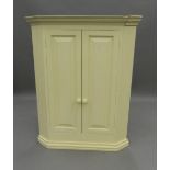 A modern white painted corner cupboard. 107.5 cm high. The property of Germaine Greer.