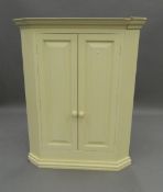 A modern white painted corner cupboard. 107.5 cm high. The property of Germaine Greer.