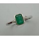 A 9 ct white gold emerald and diamond three stone ring. Ring size O/P.