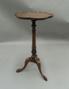 A mahogany occasional table with scalloped top, on tripod legs. 67 cm high, 35 cm diameter.