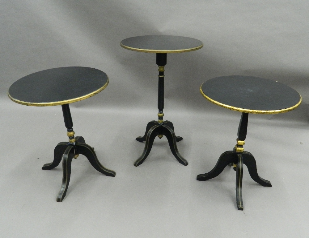 A matched set of three black and gold painted side tables. The largest 72 cm high.