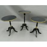 A matched set of three black and gold painted side tables. The largest 72 cm high.