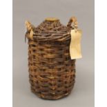A Royal Navy wicker clad stoneware flagon, full and sealed, with supply depot label. 34 cm high.