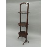 An Edwardian mahogany folding cake stand. 90 cm high.