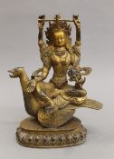 A gilt bronze model of a multi-armed deity seated on a bird, with cabochon decorations. 25 cm high.