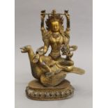 A gilt bronze model of a multi-armed deity seated on a bird, with cabochon decorations. 25 cm high.